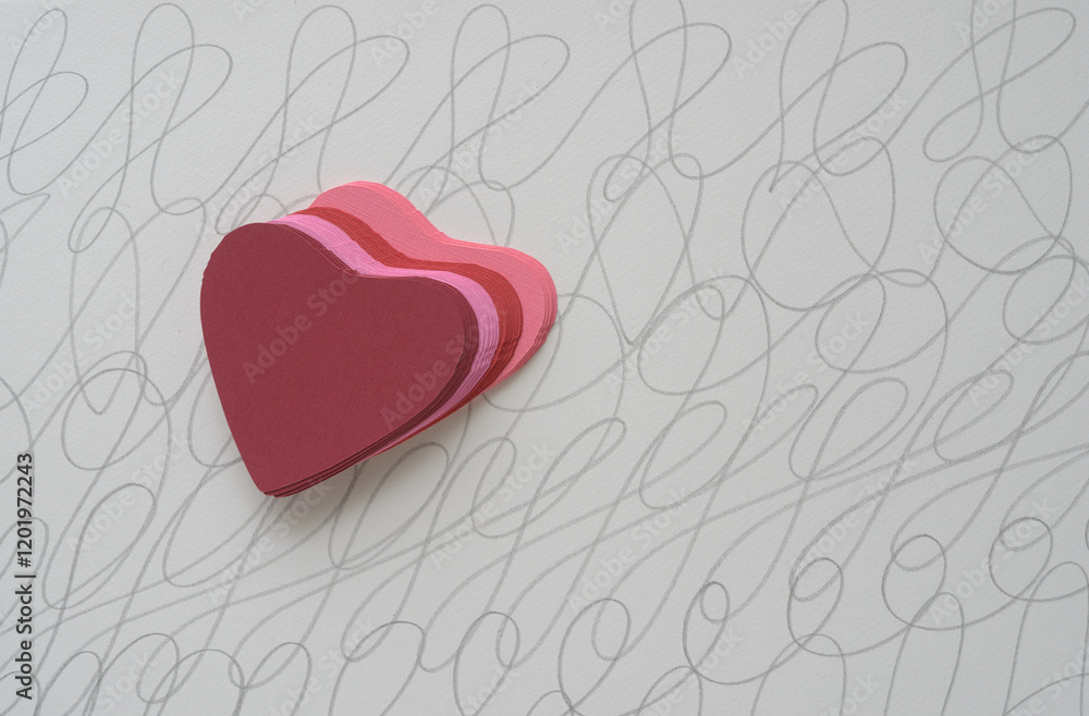 pile of machine-cut pink and red hearts on a decorative wavy line background pile of machine-cut pink and red hearts on a decorative wavy line background