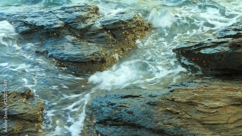 A time lapse footage of a rocky beach and moving sea water. 4K 3840x2160, zoom out to medium shot.