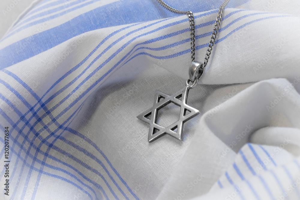Star of David (Magen David) necklace on white-blue fabric.
