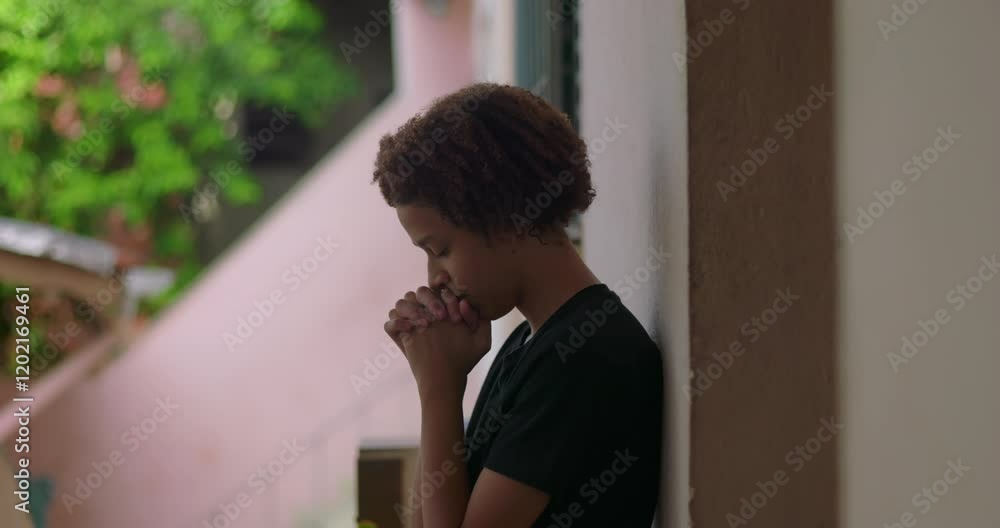 One Hispanic young boy of African descent with curly hair, eyes closed, hands clasped in prayer, reflecting spiritually, quiet outdoor moment, deep in thought, introspective pause One Hispanic young boy of African descent with curly hair, eyes closed, hands clasped in prayer, reflecting spiritually, quiet outdoor moment, deep in thought, introspective pause