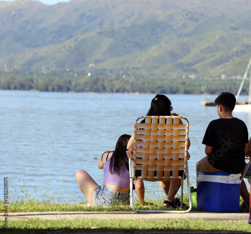 Family of tourists on a picnic on the shores of the lake in Villa Carlos Paz, Córdoba, Argentina.