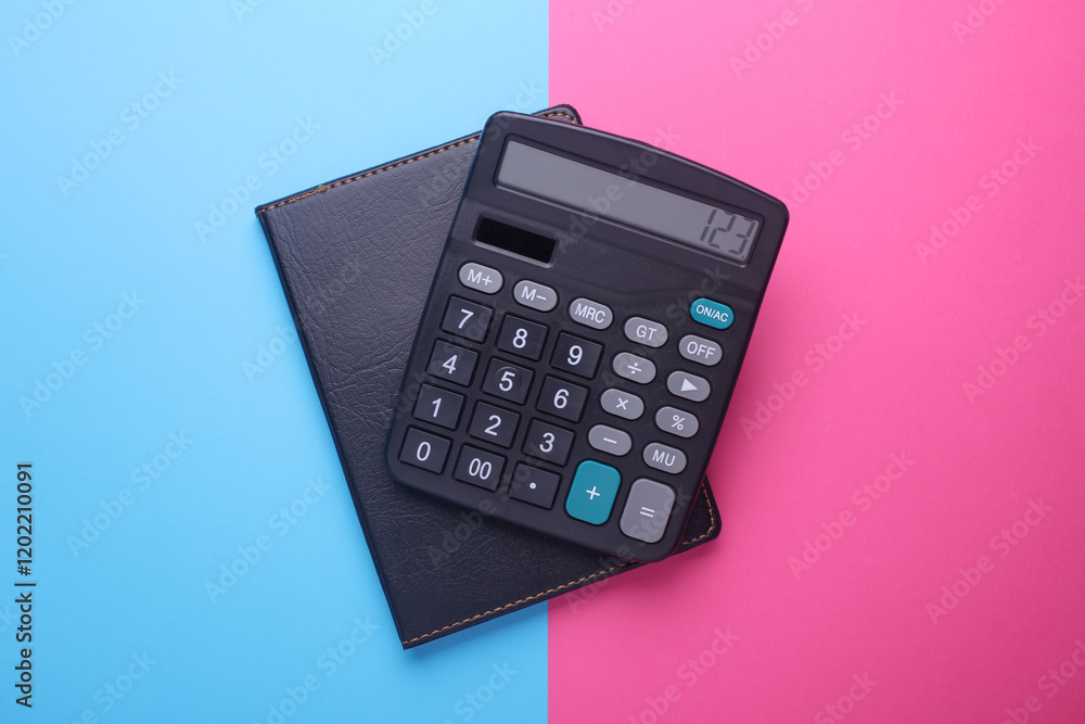 Black classic calculator and notebook on pink blue background. Top view Black classic calculator and notebook on pink blue background. Top view