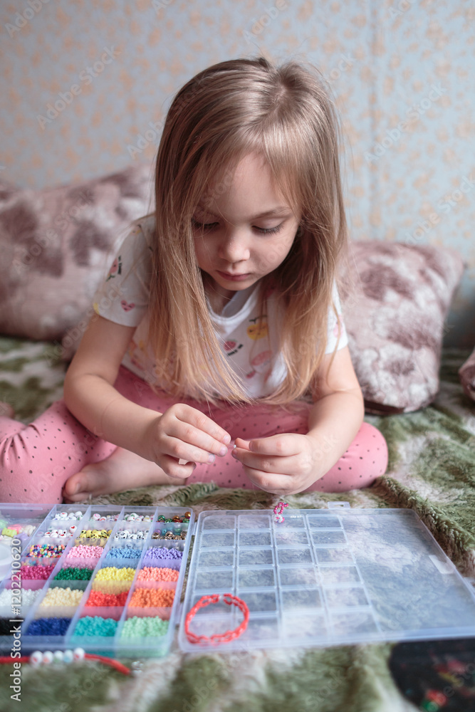 A little girl collects colorful beads near her house. Educational game, child, relaxation. A little girl collects colorful beads near her house. Educational game, child, relaxation.