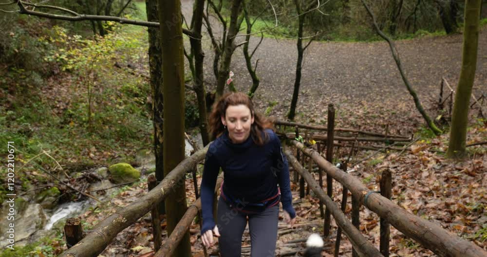 A woman is running with her dog up a flight of wooden steps in a forest. A woman is running with her dog up a flight of wooden steps in a forest.