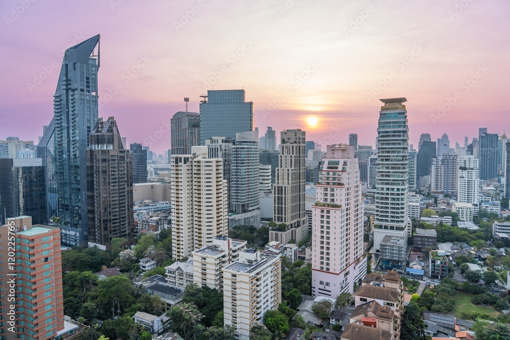 Fototapeta premium Urban skyline of Bangkok during sunset with buildings reflecting golden light