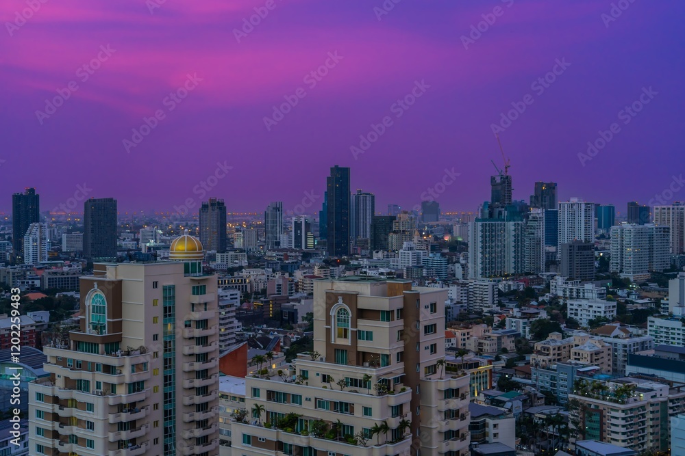 Obraz premium Vibrant sunset colors illuminate the skyline of Bangkok with towering buildings and a bustling urban landscape