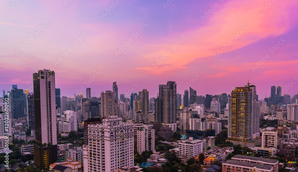 Obraz premium Sunset over a bustling city skyline with colorful clouds and modern architecture