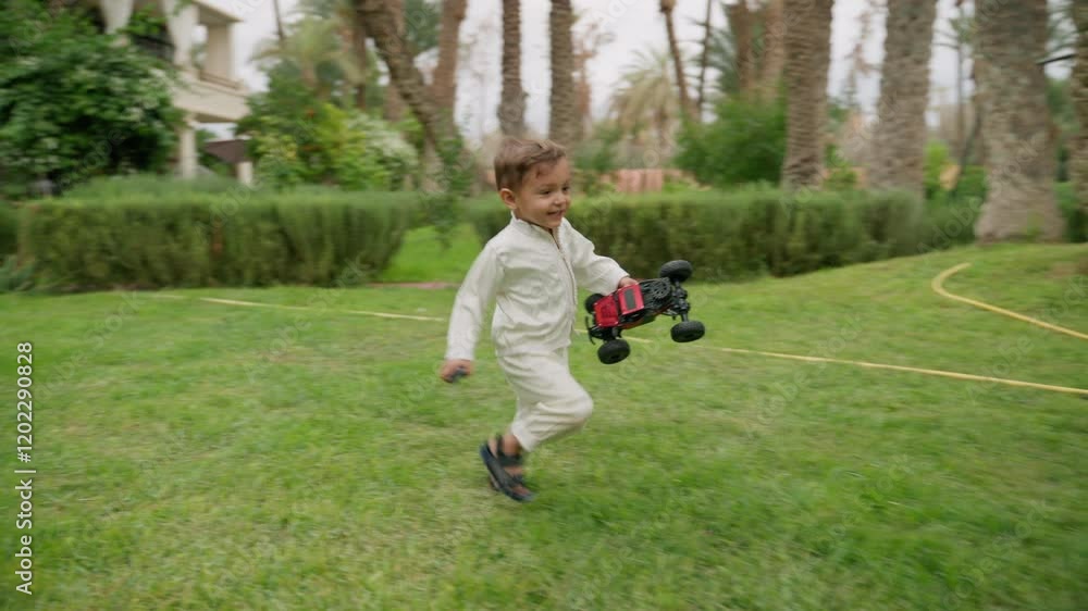 Boy runs through vibrant garden holding toy car, full of energy and joy. He approaches his mother sitting on grass, then joins her, creating warm and playful family scene in serene setting Boy runs through vibrant garden holding toy car, full of energy and joy. He approaches his mother sitting on grass, then joins her, creating warm and playful family scene in serene setting