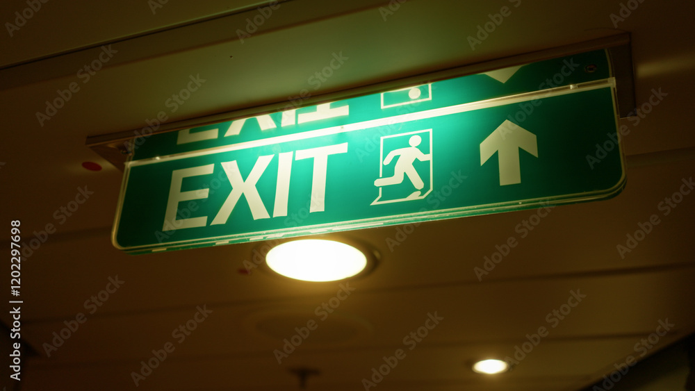 Illuminated exit sign glows green with a directional arrow indoors signaling safety in a modern building hallway highlighting emergency preparedness effectively at night. Illuminated exit sign glows green with a directional arrow indoors signaling safety in a modern building hallway highlighting emergency preparedness effectively at night.