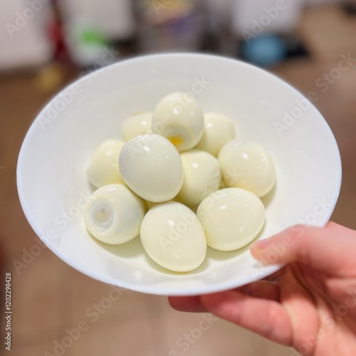in a white ceramic bowl there are ten boiled and peeled eggs . kitchen