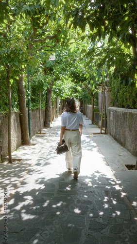 Wallpaper Mural Woman walking under green trees on a sunny day in capri, italy, enjoying the picturesque town atmosphere surrounded by lush foliage and european charm. Torontodigital.ca