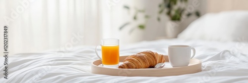 Wooden tray with tasty breakfast including croissant, orange juice and coffee placed on comfortable bed with white sheets in cozy hotel room during summer vacation photo