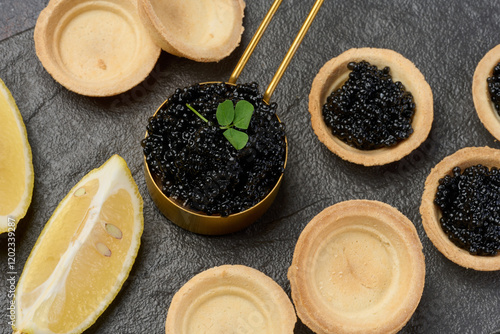 Canvastavla Black sturgeon caviar and empty round tartlets on table, top view