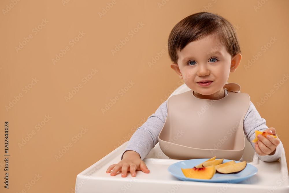 Healthy baby food. Cute little kid eating fruits in high chair on beige background, space for text Healthy baby food. Cute little kid eating fruits in high chair on beige background, space for text
