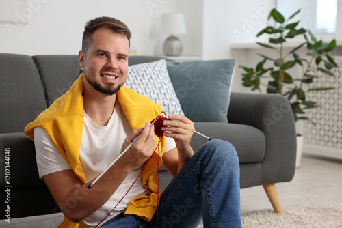 Man knitting with needles on floor at home photo