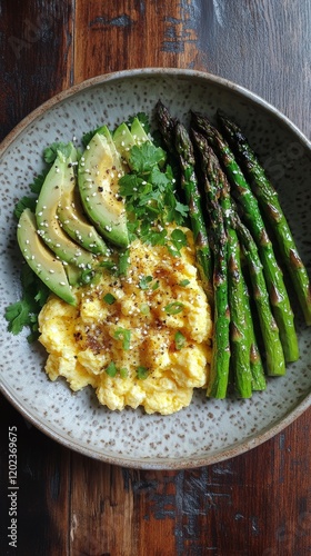 Healthy breakfast plate with scrambled eggs, asparagus, and avocado arranged ...