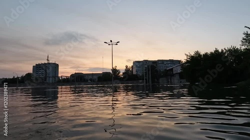 Flooded streets in Kherson town with beautiful sunset at background. Explosion of dam on Dnipro river in city of Novaya Kakhovka. Consequences of detonation of Kakhovka Hydroelectric Power Station photo