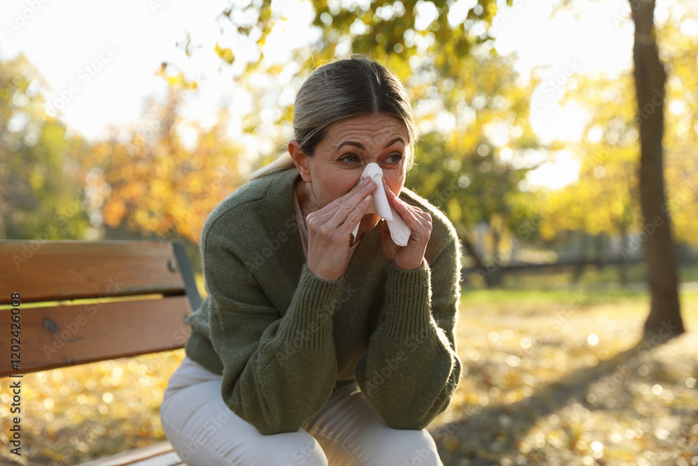Woman with runny nose on wooden bench in park Woman with runny nose on wooden bench in park