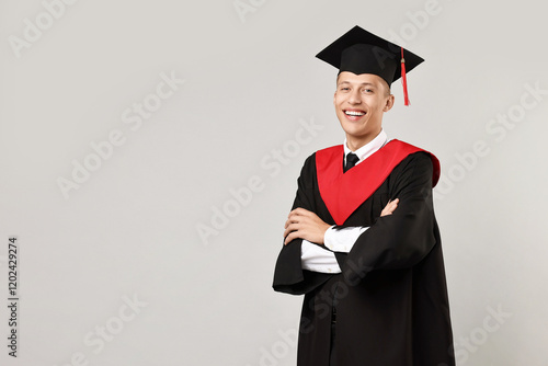 Happy student with crossed arms after graduation on grey background. Space for text photo