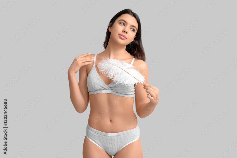Beautiful young woman with soft feather on grey background. Epilation concept Beautiful young woman with soft feather on grey background. Epilation concept