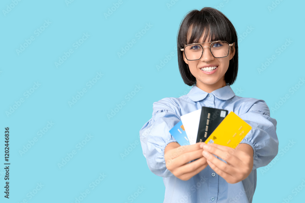 Beautiful young woman with credit cards on blue background Beautiful young woman with credit cards on blue background