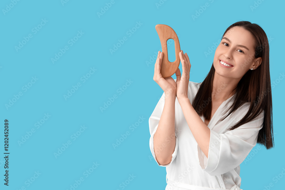 Young woman with wooden massage tool on blue background Young woman with wooden massage tool on blue background