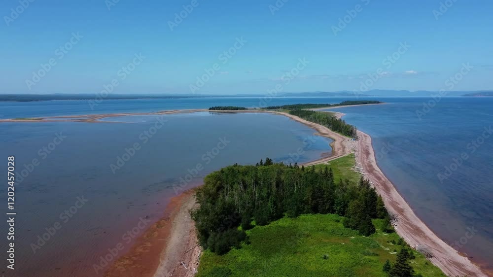 Panoramic aerial view of a tranquil and green sandy coastal peninsula bathing in a vast azure sea under a blue sky. Panoramic aerial view of a tranquil and green sandy coastal peninsula bathing in a vast azure sea under a blue sky.