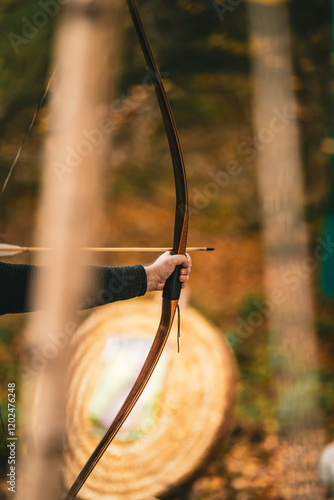 A man is holding a bow and arrow, aiming at a target