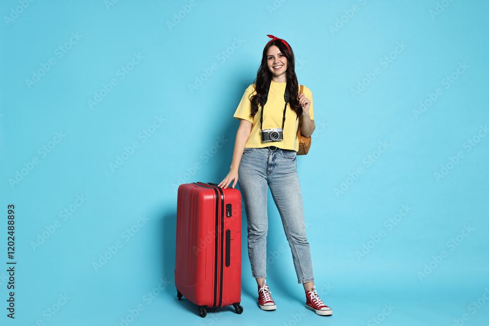 Young tourist with camera and suitcase on light blue background Young tourist with camera and suitcase on light blue background