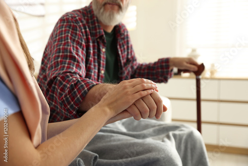 Caregiver supporting senior man on sofa indoors, closeup. Home health care service photo