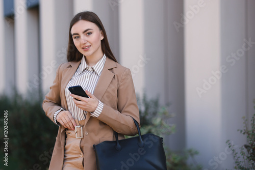 Businesswoman in stylish suit with smartphone outdoors. Space for text photo