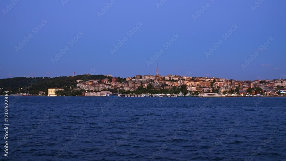 This video showcases Istanbul during the blue hour, with the Bosphorus in the foreground and hillside homes illuminated. The iconic Çamlıca Tower rises above, blending modernity and tradition in seren This video showcases Istanbul during the blue hour, with the Bosphorus in the foreground and hillside homes illuminated. The iconic Çamlıca Tower rises above, blending modernity and tradition in seren