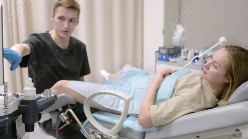 A gynecologist - ultrasound specialist performs an intervaginal ultrasound during a woman's appointment. Doctor shows an image of an early pregnancy on the ultrasound screen. IVF treatment protocols
