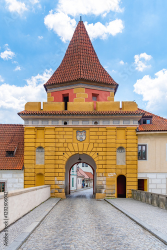 The vibrant yellow Budejovicka Gate stands majestically under a blue sky, inviting visitors to explore the historic streets of Cesky Krumlov. photo