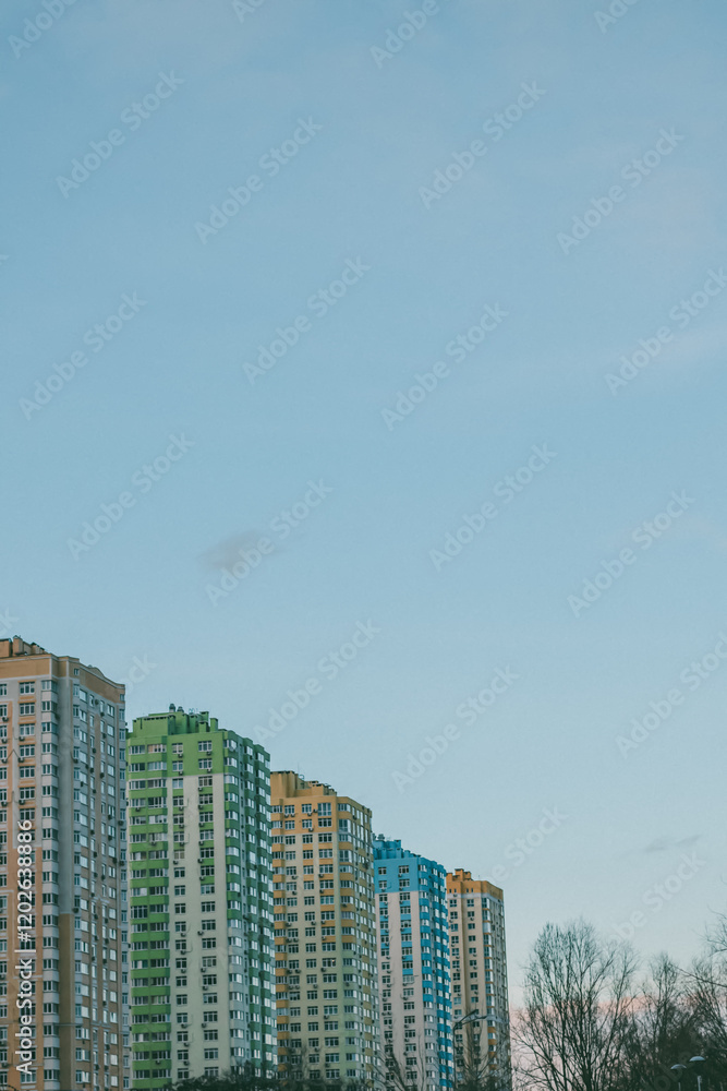 Tall residential buildings in a diagonal row with multi-colored facades under a clear blue sky, captured during early spring. Urban cityscape outdoors. Tall residential buildings in a diagonal row with multi-colored facades under a clear blue sky, captured during early spring. Urban cityscape outdoors.