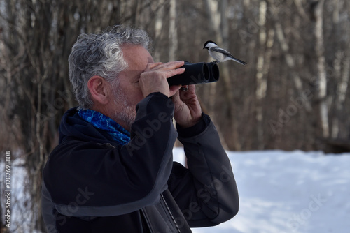 Black Capped Chickadee sitting on the binoculars of a bird watcher.  Humorous and unexpected portrait!