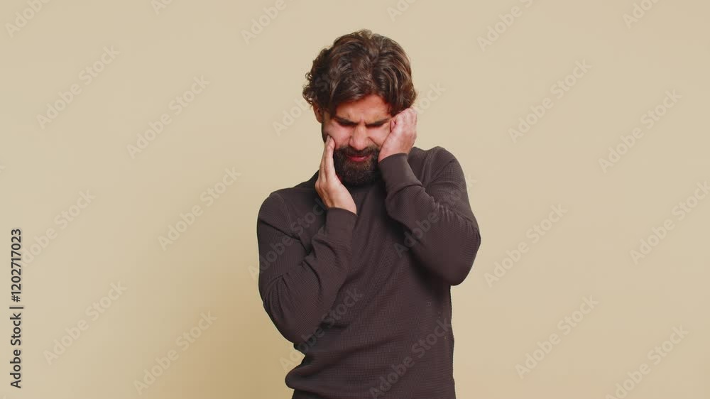 Indian bearded man touching sore cheek suffering from toothache cavities or gingivitis waiting for dentist appointment gums disease. Handsome Hindu guy indoors studio shot isolated on beige background Indian bearded man touching sore cheek suffering from toothache cavities or gingivitis waiting for dentist appointment gums disease. Handsome Hindu guy indoors studio shot isolated on beige background