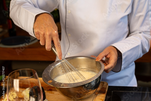 Chef batendo mistura em uma tigela de inox na cozinha