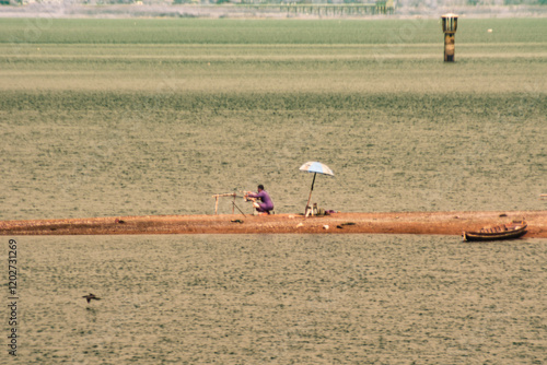 An infrared style, a person sitting on a small strip of land surrounded by water photo