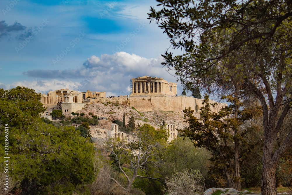 Fototapeta premium Majestic Parthenon on a mountain among the trees, with a blue sky in the background, Athens, Greece