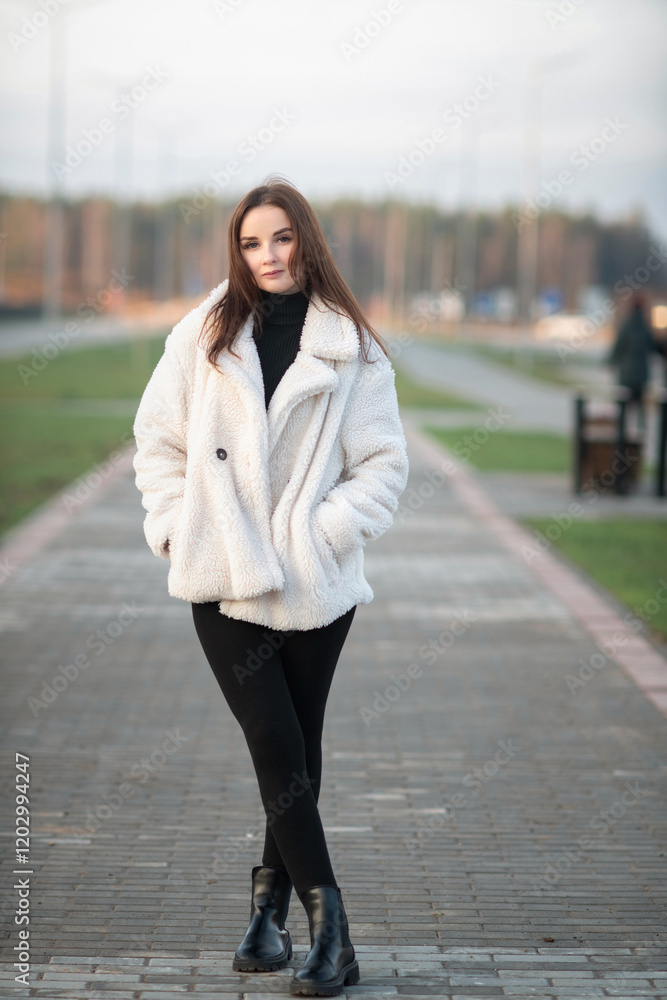 Fototapeta premium Beautiful young dark-haired girl in an urban environment in early spring.