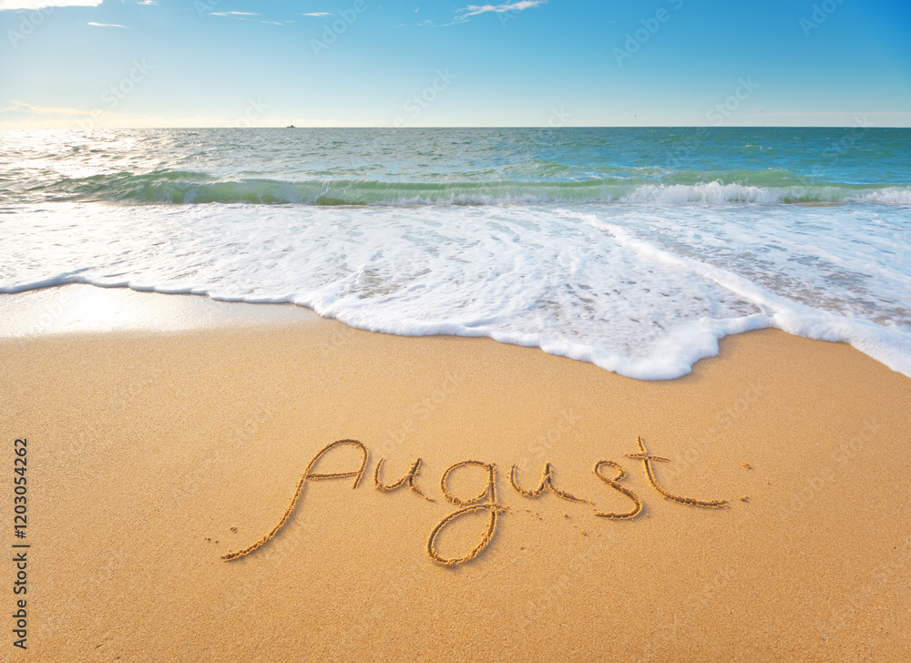 August word written on sea sand shore beach at day. August word written on sea sand shore beach at day.