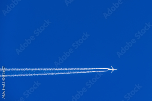 Aeroplane with white vapor trails flying on a blue sky