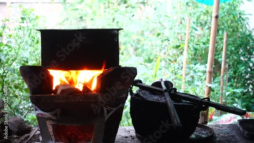 In a simple and old-fashioned way, cooking food with a stainless steel pot and an Anglo charcoal stove. to get a dark sooty color over a long time. The charcoal stove has a red light on it.