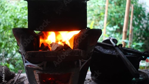 In a simple and old-fashioned way, cooking food with a stainless steel pot and an Anglo charcoal stove. to get a dark sooty color over a long time. The charcoal stove has a red light on it.