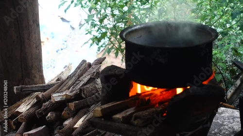 In a simple and old-fashioned way, cooking food with a stainless steel pot and an Anglo charcoal stove. to get a dark sooty color over a long time. The charcoal stove has a red light on it.