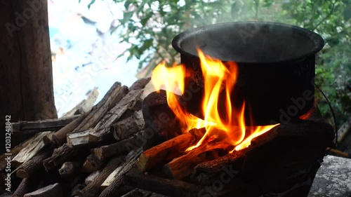 In a simple and old-fashioned way, cooking food with a stainless steel pot and an Anglo charcoal stove. to get a dark sooty color over a long time. The charcoal stove has a red light on it.