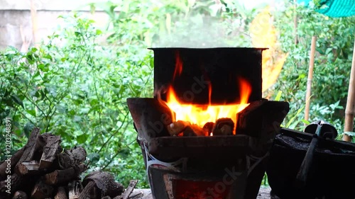 In a simple and old-fashioned way, cooking food with a stainless steel pot and an Anglo charcoal stove. to get a dark sooty color over a long time. The charcoal stove has a red light on it.