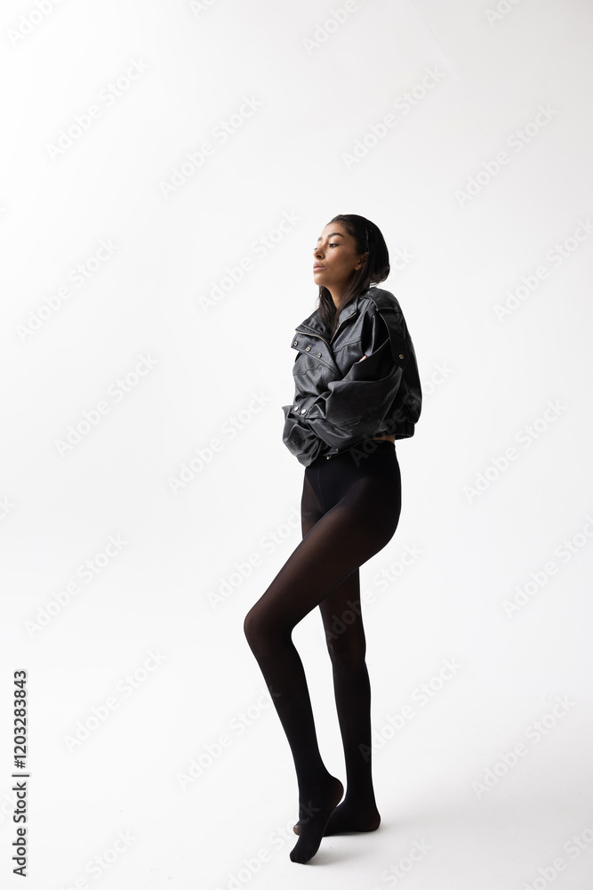 Beautiful young Arab woman wears black jacket posing over white wall. Vertical. Beautiful young Arab woman wears black jacket posing over white wall. Vertical.