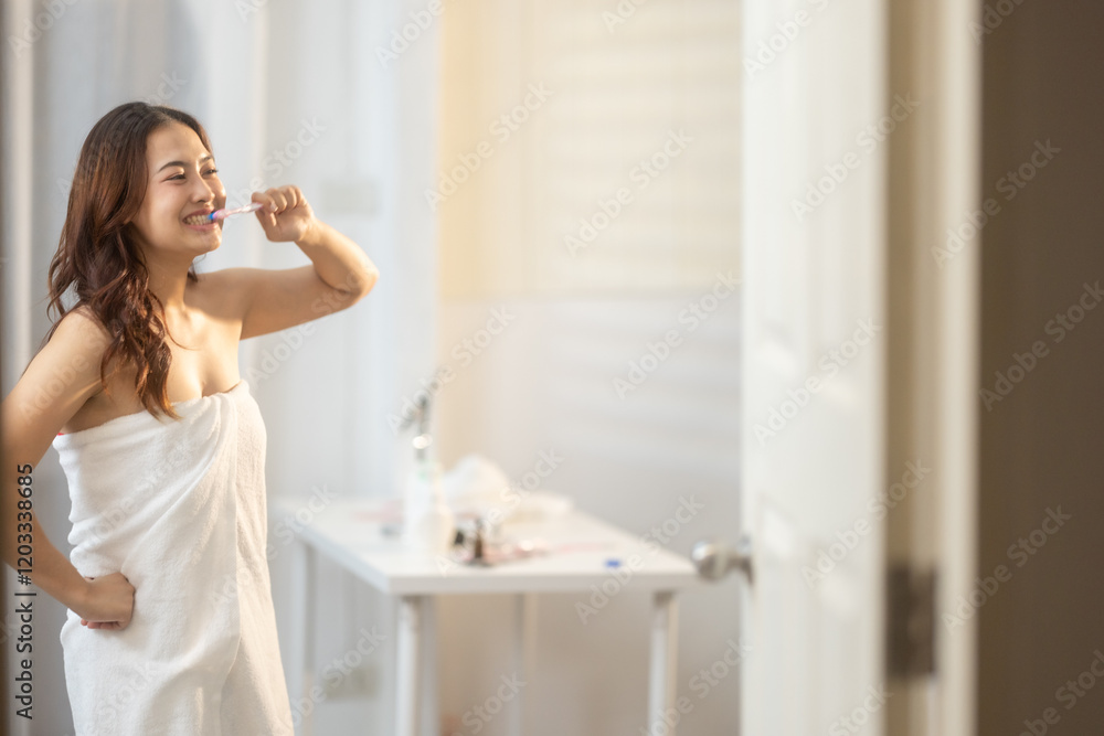 Woman smiling while brushing teeth in a bright bathroom after a fresh shower Woman smiling while brushing teeth in a bright bathroom after a fresh shower